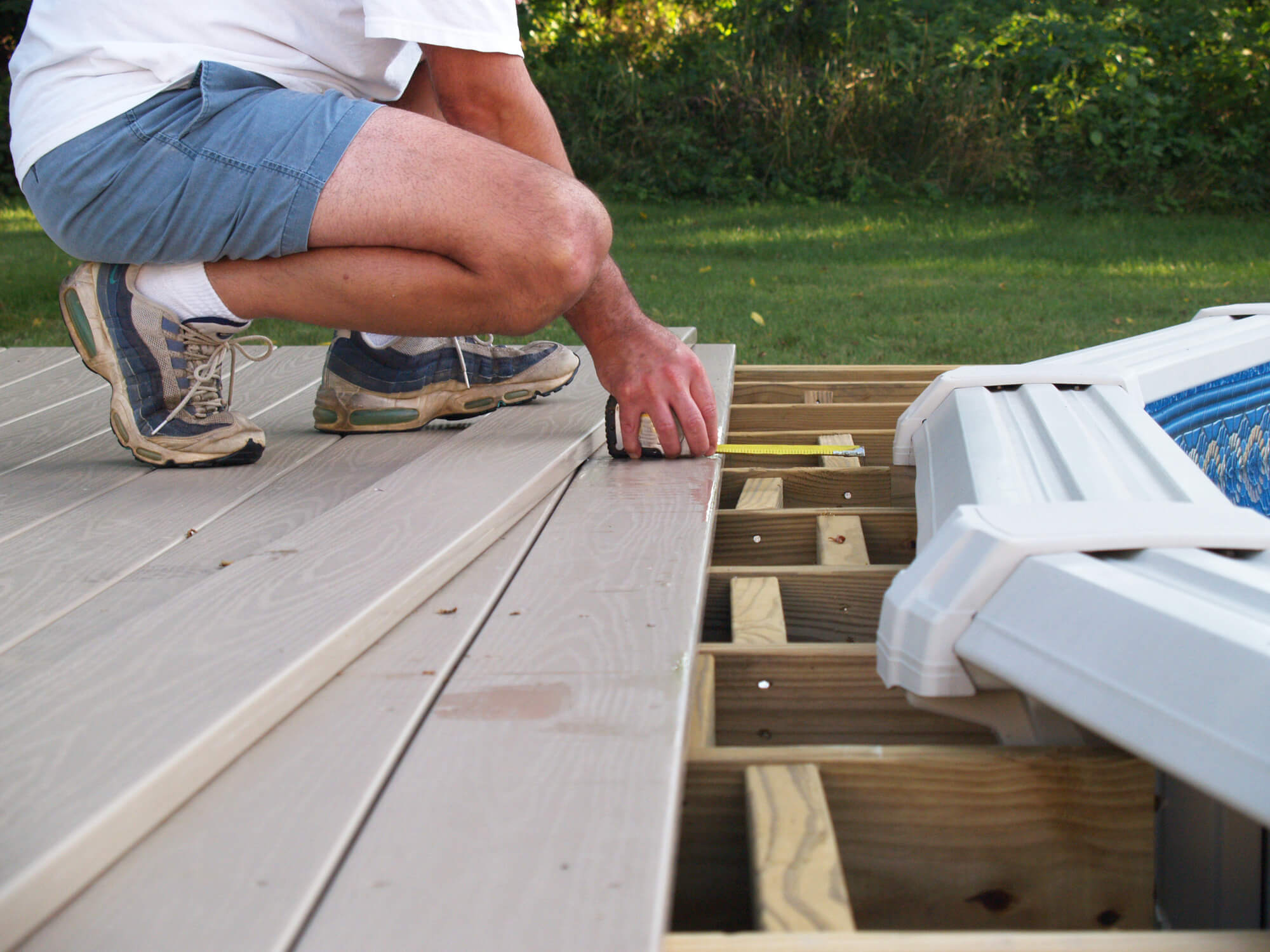 A landscaper is doing a decking in the garden.